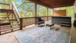 Una terrazza esterna coperta con una scala in legno, un'area relax con una poltrona e poggiapiedi e una vasca idromassaggio.