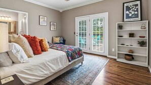 Una camera da letto con un letto, una ventola a soffitto, un'ampia finestra e una porta che dà su un balcone.