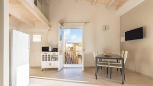 A spacious room with a dining area, a kitchen, and a balcony with a view. - Ca Rouge - Modern Bright 3BR Boutique Retreat in the Heart of Carloforte (Carloforte)