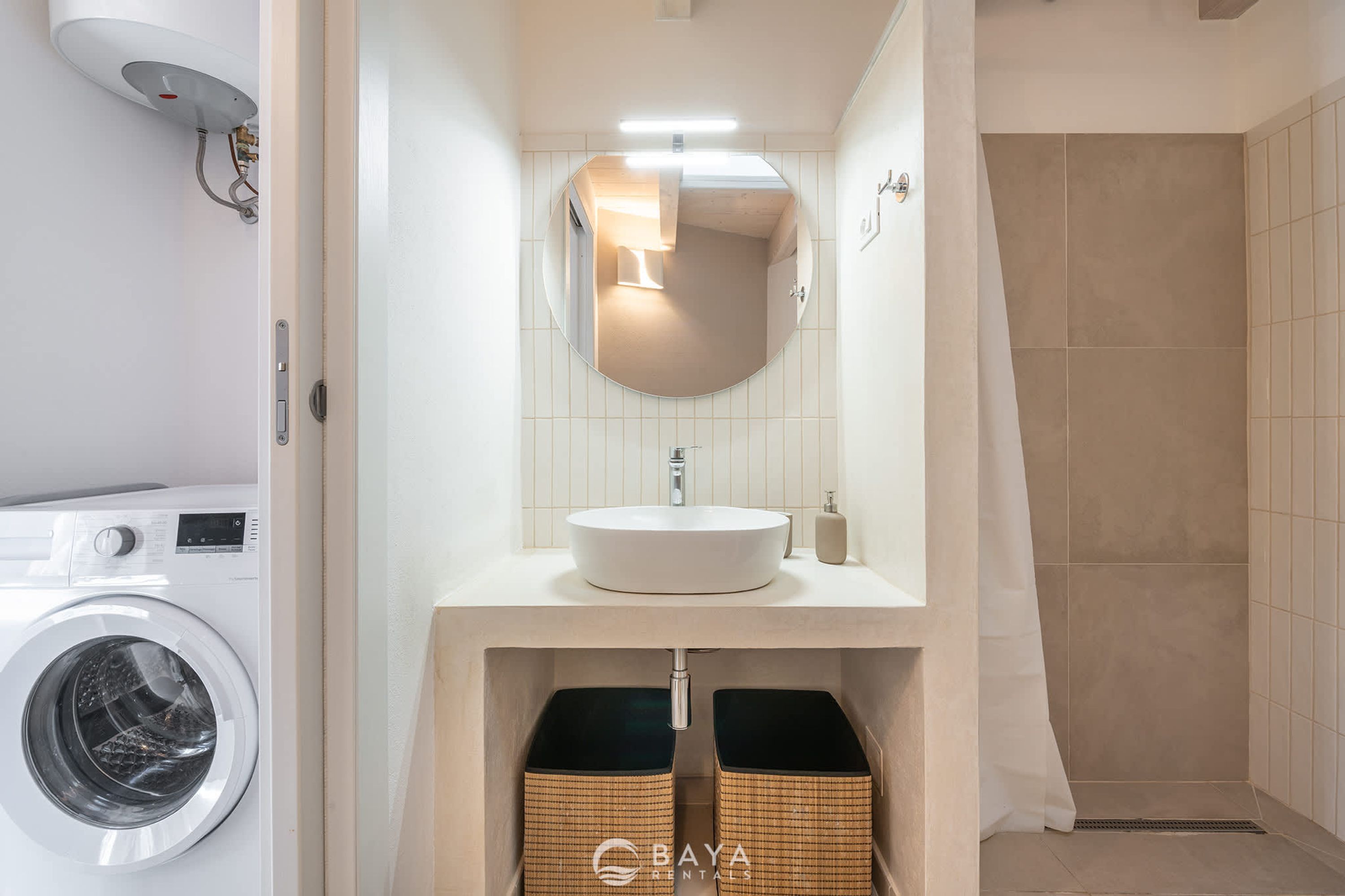A modern bathroom with a built-in washing machine, a sink with a mirror, and a shower area.