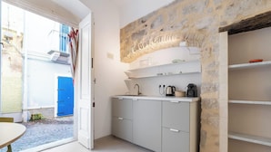 A compact kitchen with a stone accent wall, a built-in sink, and a small countertop. - Ca Rouge - Modern Bright 3BR Boutique Retreat in the Heart of Carloforte (Carloforte)