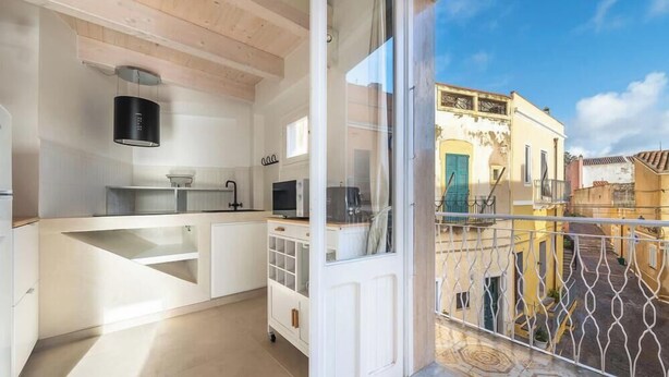 A modern kitchen with white cabinetry, a built-in oven, and a sliding glass door leading to a courtyard. - Ca Rouge - Modern Bright 3BR Boutique Retreat in the Heart of Carloforte (Carloforte)