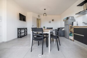A modern kitchen with a dining area, a flat-screen TV, and a built-in oven. - Modern 2BR Retreat in Pula - Bright Quiet (Pula)