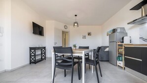 A modern kitchen with a built-in oven, a refrigerator, and a dining area with a table and chairs. - Modern 2BR Retreat in Pula - Bright Quiet (Pula)