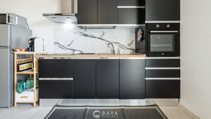 A modern kitchen with black cabinets, a marble backsplash, a built-in oven, and a microwave. - Modern 2BR Retreat in Pula - Bright Quiet (Pula)