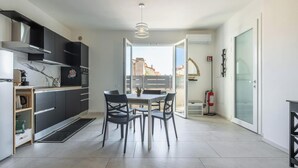 A modern kitchen with a dining area, a view through a glass door, and a fire extinguisher. - Modern 2BR Retreat in Pula - Bright Quiet (Pula)