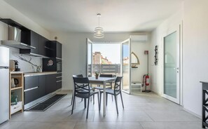 A modern kitchen with black cabinets, a marble backsplash, and a dining area with a table and chairs. - Modern 2BR Retreat in Pula - Bright Quiet (Pula)