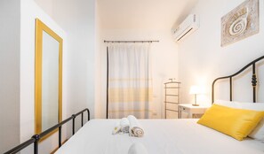 A hotel room with a bed, a mirror, a towel rack, a nightstand, a lamp, and an air conditioner. - Casa Vittoria in Quartu Sant Elena (Quartu Sant'Elena)