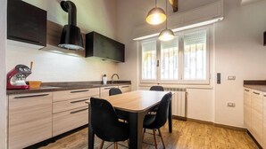 A modern kitchen with a dining table, chairs, and a built-in oven. - Seaside Villa Apartment With Beach Access (Quartu Sant'Elena)