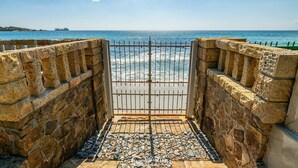 A stone-walled entrance with a metal gate leading to a beach. - Seaside Villa Apartment With Beach Access (Quartu Sant'Elena)
