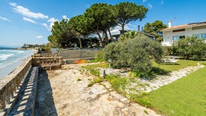 A coastal property with a stone pathway leading to a beach, a large tree, and a white building with a tiled roof. - Seaside Villa Apartment With Beach Access (Quartu Sant'Elena)