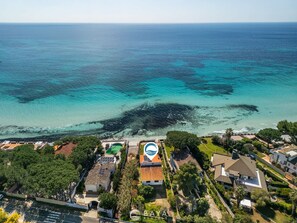 Vista aérea de una zona costera con casas, una piscina y una playa.