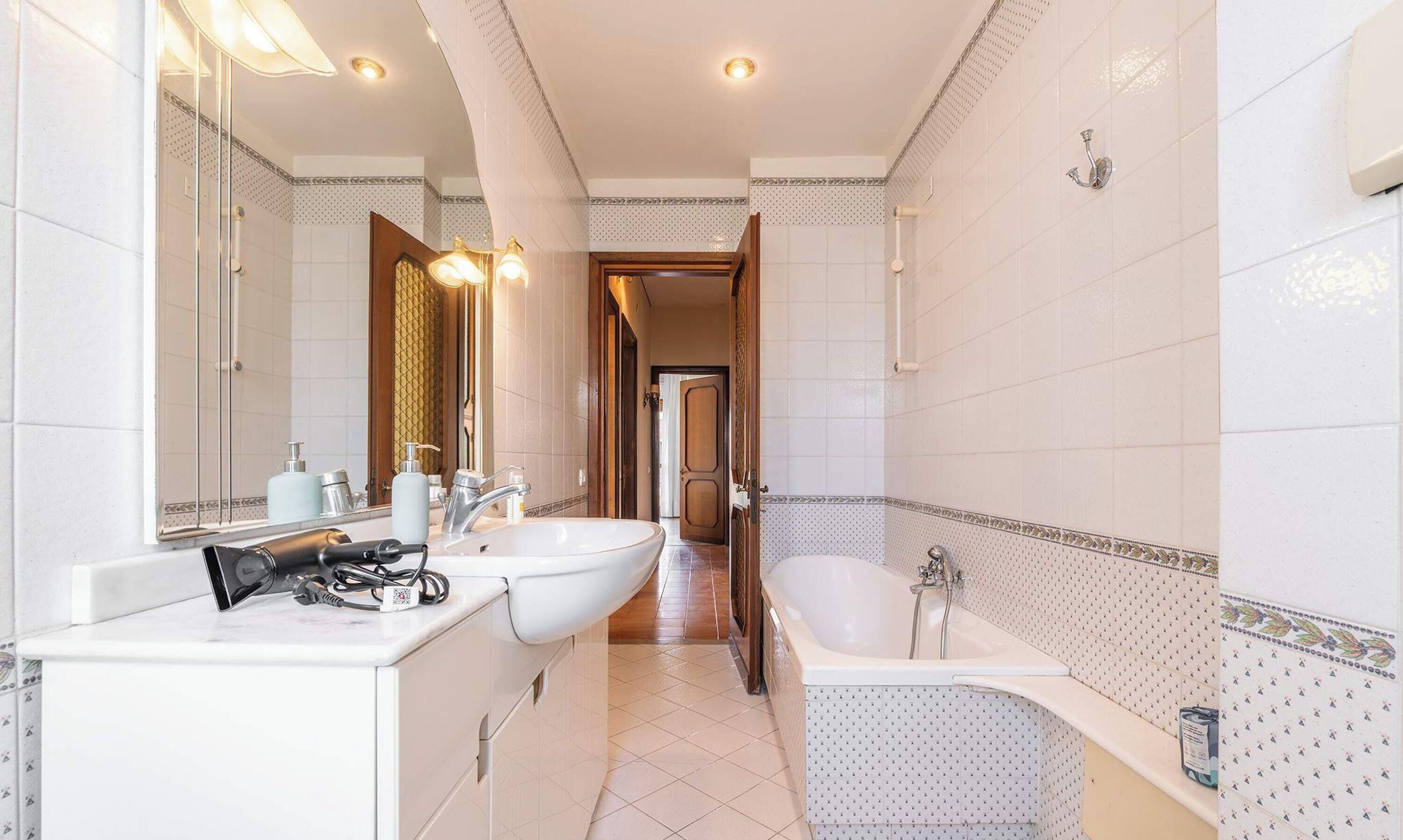 Un baño con un espejo grande, dos lavamanos, una bañera y una ducha.