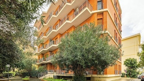 A multi-story building with balconies, surrounded by greenery. - Appartamento Generale (Cagliari)