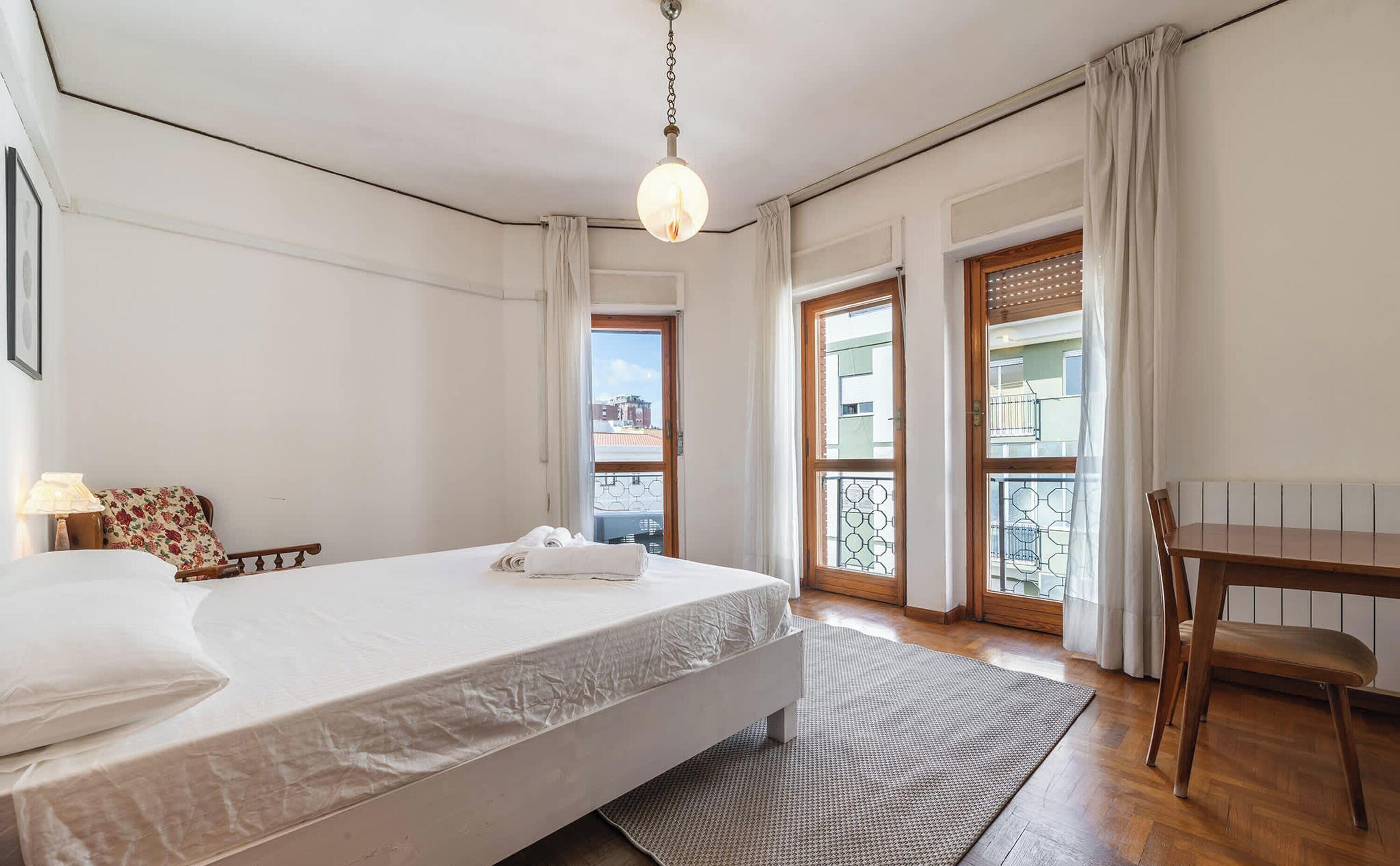 Une chambre à coucher avec un lit, un bureau et une vue sur l’extérieur.