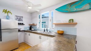 A kitchen with a refrigerator, stove, sink, and a ceiling fan. - Rincon Surf Club | BBQ | Pool | Pet Friendly (Rincon)