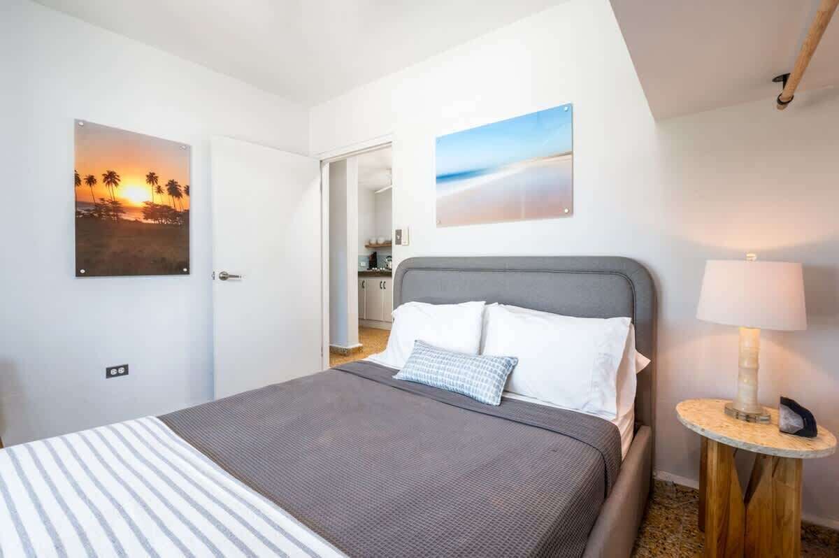 A hotel room with a bed, a lamp, and two wall art pieces.
