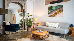 Una sala de estar con sofá, sillón, mesa de centro y un espejo grande.