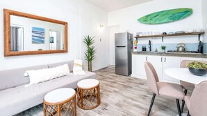 Ein kompakter Wohnbereich mit einer Küchenzeile, einem Essbereich und einer Sitzecke mit Sofa und runden Tischen.