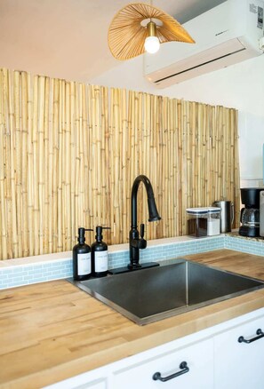 Una cocina con pared de bambú, grifo negro y cafetera.