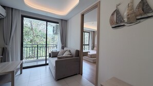 Une chambre d’hôtel moderne dotée d’un balcon, d’un canapé, d’une table à manger et d’un grand miroir.