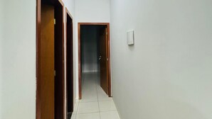 A hallway with white walls, wooden doors, and a tiled floor. - Furnished house with air conditioning in Gurupi (Gurupi)