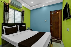 A hotel room with a bed, curtains, an air conditioning unit, a wooden door, and a television. - Super Hotel O Acropolis Mall Kolkata (Kolkata)