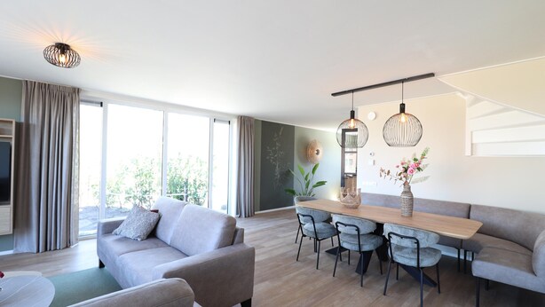 Un salon moderne avec un canapé, une table à manger, des chaises et une grande fenêtre.