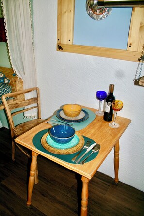 Une table à manger en bois, agrémentée d’un chemin de table bleu et doré, d’un saladier, de verres à vin et d’une bouteille de vin.
