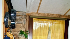 A kitchen with a tiled backsplash, a sink, and a window with yellow curtains.