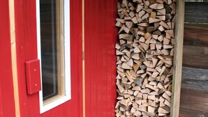 A red door with a window, a stack of firewood, and a blue carpet.