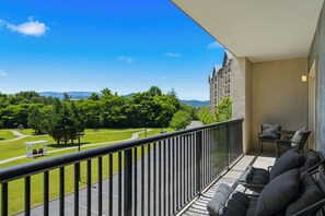 Ein Balkon mit Blick auf einen grünen Park und ferne Berge.