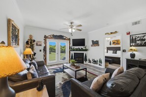 Ein Wohnzimmer mit Kamin, Deckenventilator und Fernseher.