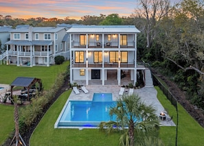 Ein zweigeschossiges Haus mit Pool, Sitzgelegenheit im Freien und einer überdachten Terrasse.