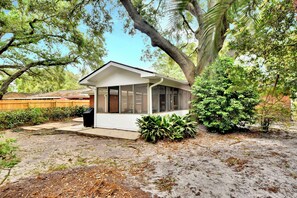 A small, single-story house with a white exterior, large windows, and a covered porch area. - Comfortable 3 bedroom/2 bath house close to the pier/village area (Saint Simons Island)