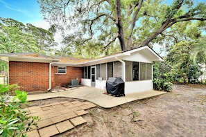 A house with a brick exterior, a covered patio, and a large tree in the background. - Comfortable 3 bedroom/2 bath house close to the pier/village area (Saint Simons Island)