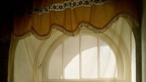 A window with a decorative curtain and a view of the interior.