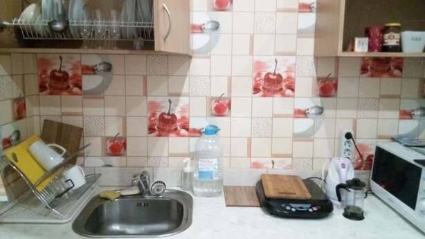 A kitchen with a sink, a dish rack, a coffee maker, and a microwave.