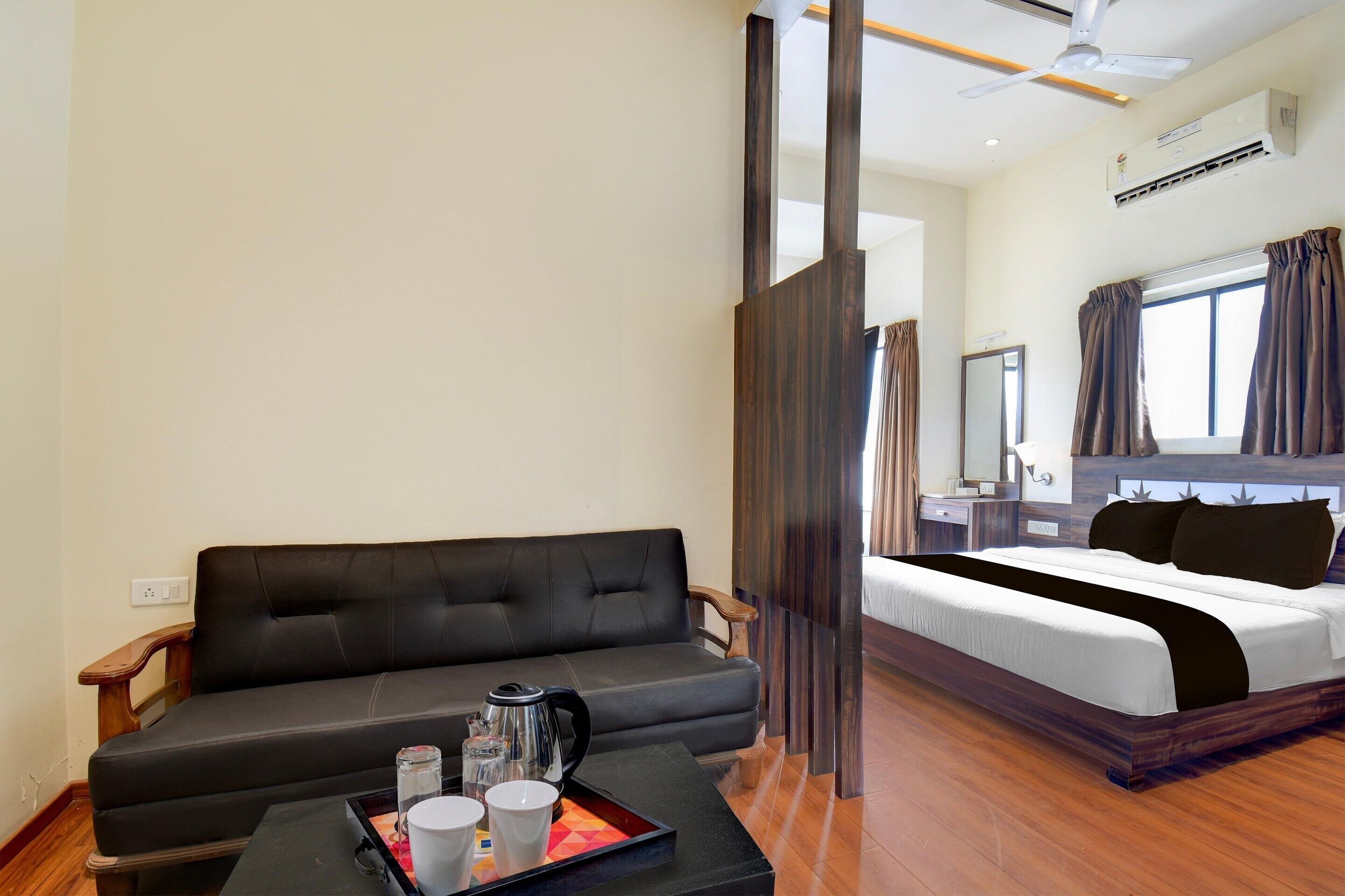 A hotel room with a bed, a sofa, a coffee table with a tray, and a ceiling fan.