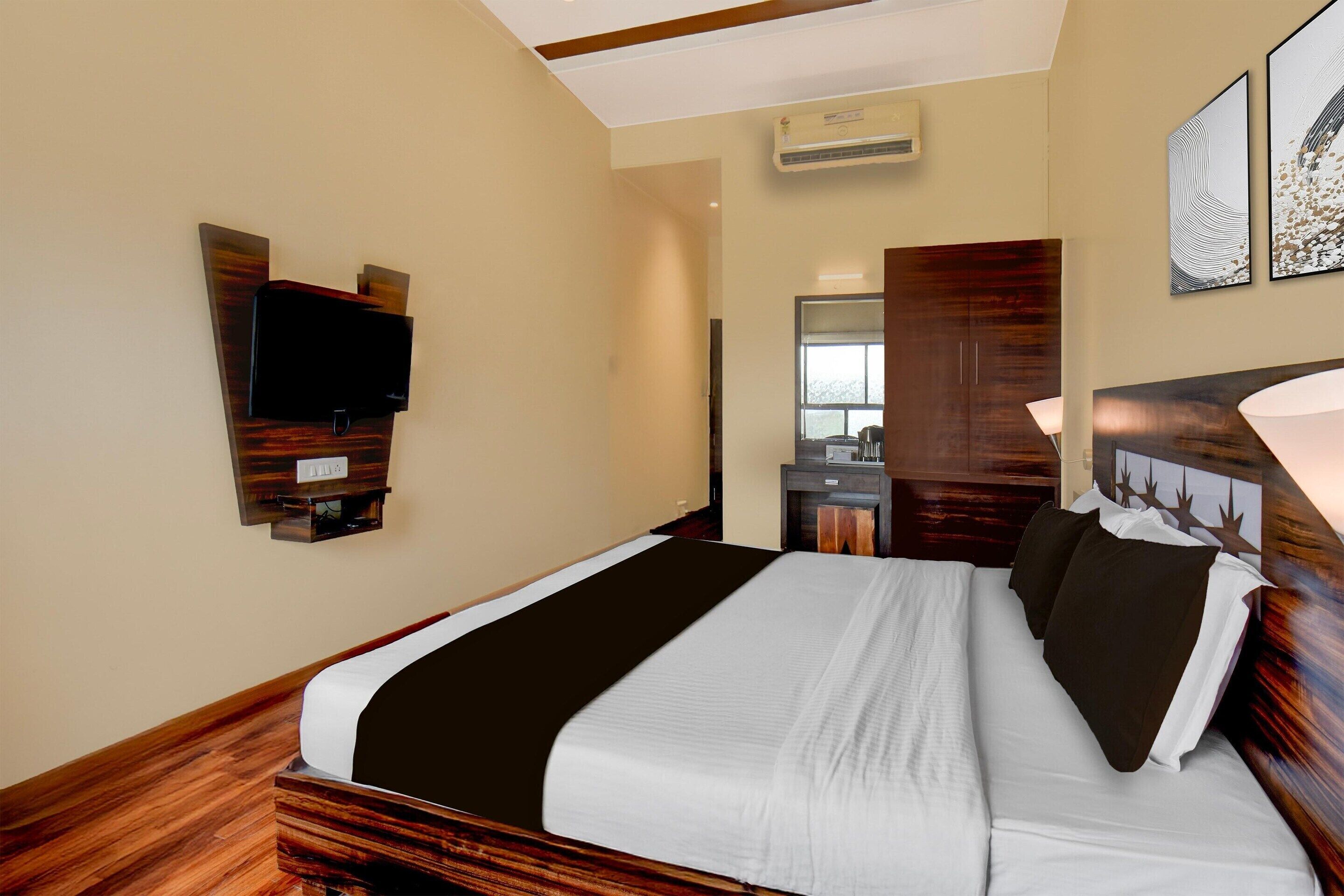 A hotel room with a bed, a television mounted on the wall, a mirror, and a wooden headboard.