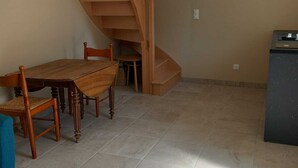 Ein Essbereich mit Holztisch und -stühlen, einer Treppe und einem Fliesenboden.