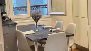 Ein Essbereich mit Tisch, Stühlen, einer Vase mit getrockneten Blumen und einem Fenster mit Blick.