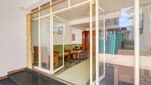 A room with a sliding glass door, a green sofa, a wooden table, and a small rug. - Classic With Balcony Madikeri (Madikeri)