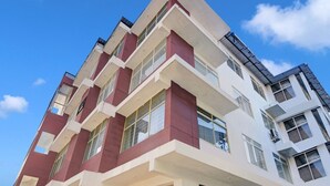 A multi-story building with a modern architectural design, featuring a combination of white and maroon colors, large windows, and a visible garage door. - Classic With Balcony Madikeri (Madikeri)
