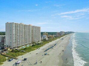 A beachfront hotel with multiple floors, a sandy beach, and a clear view of the ocean. - Crescent Shores 1007 - Oceanfront Pool (North Myrtle Beach)