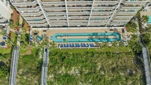 Ein Hochhotel mit mehreren Balkonen, einem Schwimmbad und einer Strandanlage.