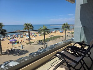 Ein Balkon mit Blick auf einen Strand, darunter geparkte Autos und ein klarer, blauer Himmel.