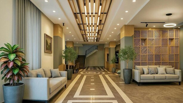 A hotel lobby with a central staircase, two sofas, potted plants, and a patterned floor.