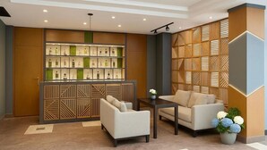 A lobby with a reception desk, seating area, and a decorative wall with a geometric pattern.