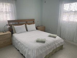 A bedroom with a bed, nightstands, a lamp, and sheer curtains. - Bring your motorboat: Simple Old Florida Style Home (Englewood)